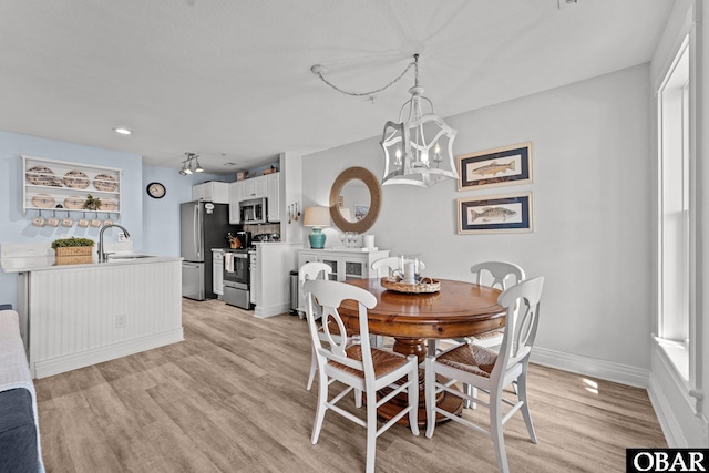 dining area featuring baseboards, an inviting chandelier, and light wood-type flooring