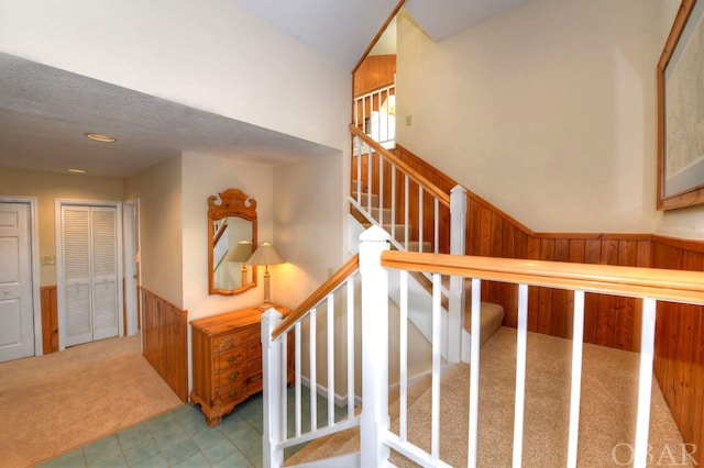 staircase featuring carpet floors, wainscoting, and wooden walls