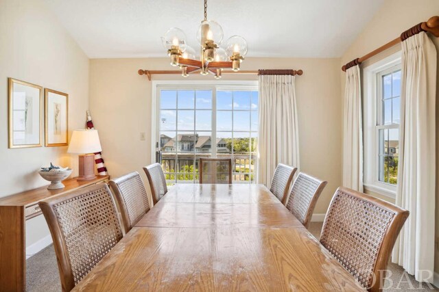 dining space featuring an inviting chandelier, baseboards, vaulted ceiling, and a wealth of natural light