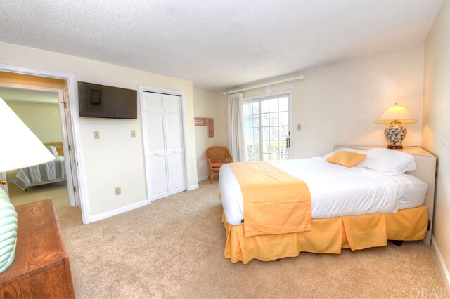 carpeted bedroom with a closet, a textured ceiling, and baseboards