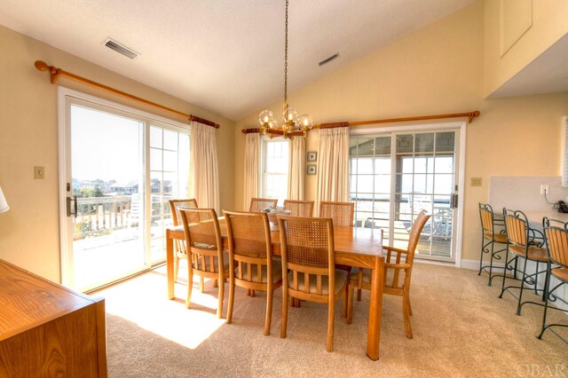 dining room with light colored carpet, vaulted ceiling, visible vents, and an inviting chandelier