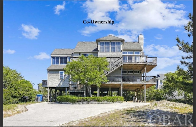 view of front facade with a carport, a chimney, concrete driveway, and a wooden deck