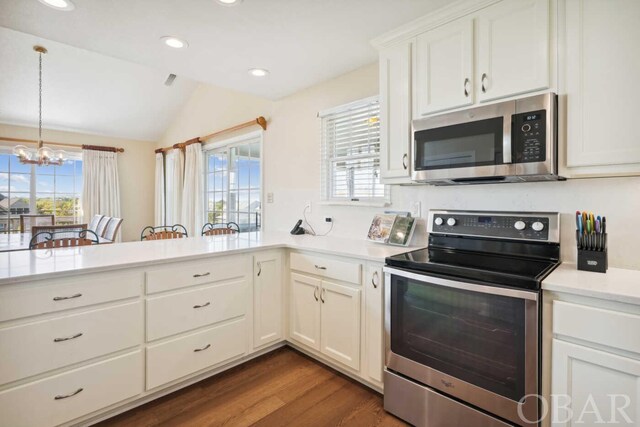 kitchen featuring a wealth of natural light, stainless steel appliances, light countertops, and decorative light fixtures