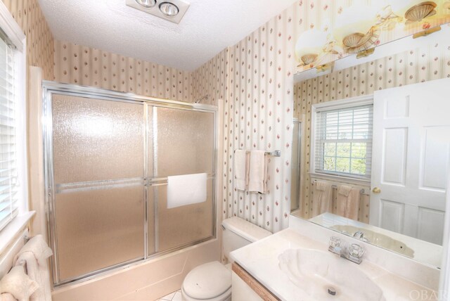 bathroom with enclosed tub / shower combo, a textured ceiling, toilet, and wallpapered walls