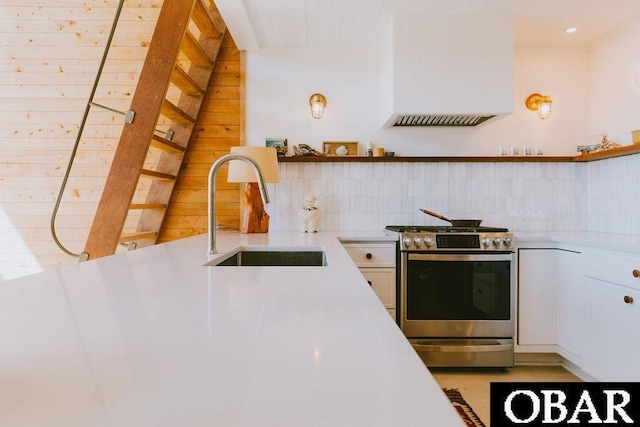 kitchen featuring stainless steel range with gas cooktop, open shelves, a sink, and light countertops