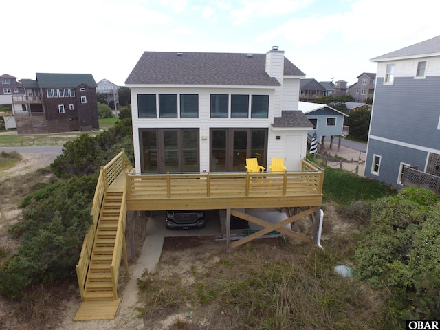 back of house featuring a residential view, roof with shingles, a chimney, stairs, and a deck