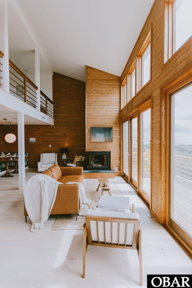living area with high vaulted ceiling, a large fireplace, and wooden walls