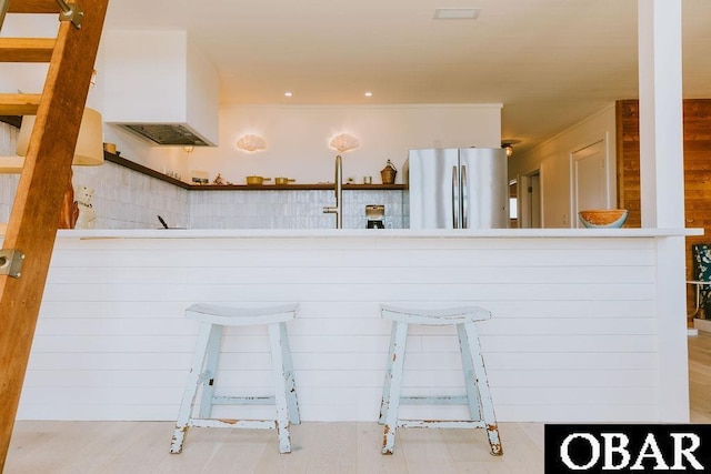 kitchen with open shelves, custom range hood, a kitchen bar, visible vents, and freestanding refrigerator