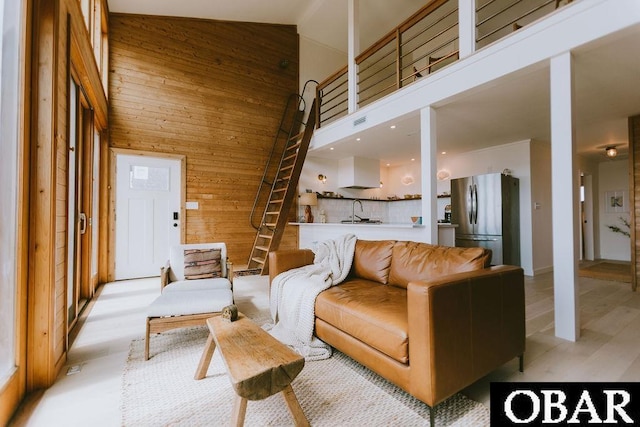living area featuring high vaulted ceiling, wood walls, and visible vents