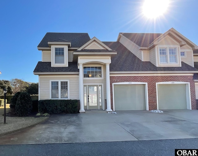 view of front of home featuring driveway, roof with shingles, and brick siding