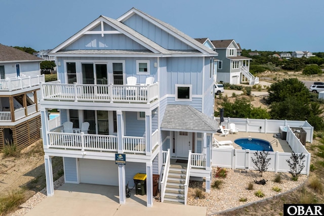 1206 Windance Ln Lot 103, Corolla, NC 27927 - view of front of property with board and batten siding, a garage, a fenced backyard, concrete driveway, and a balcony