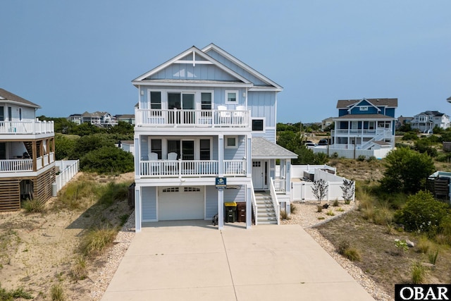 1206 Windance Ln Lot 103, Corolla, NC 27927 - coastal inspired home with board and batten siding, a balcony, concrete driveway, a garage, and stairway