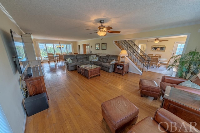 living area featuring light wood-type flooring, stairway, a textured ceiling, and ornamental molding