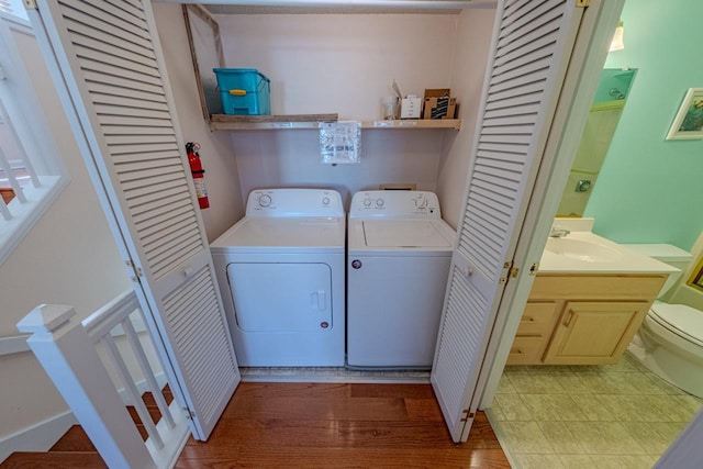 washroom featuring laundry area, wood finished floors, a sink, and washer and dryer