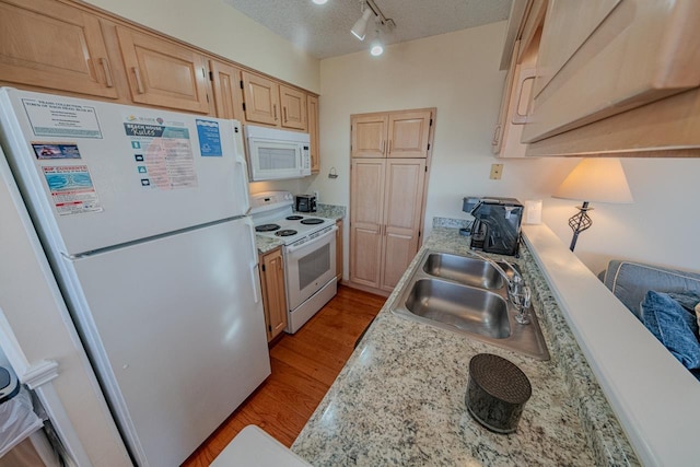 kitchen featuring white appliances, light wood-style flooring, light brown cabinets, and a sink