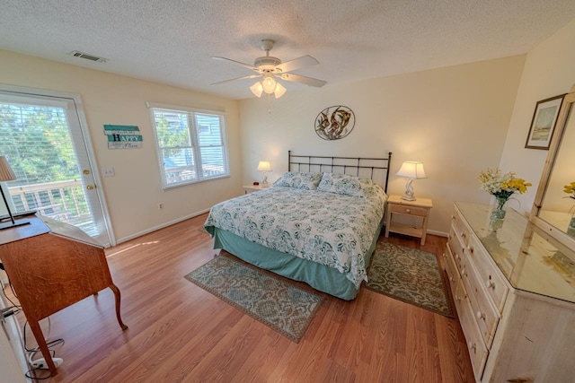 bedroom featuring access to exterior, visible vents, light wood-style flooring, ceiling fan, and a textured ceiling