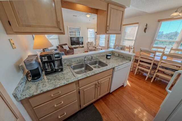 kitchen featuring white dishwasher, a textured ceiling, light wood-type flooring, light brown cabinets, and a sink