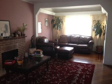 living room with a brick fireplace and hardwood / wood-style flooring