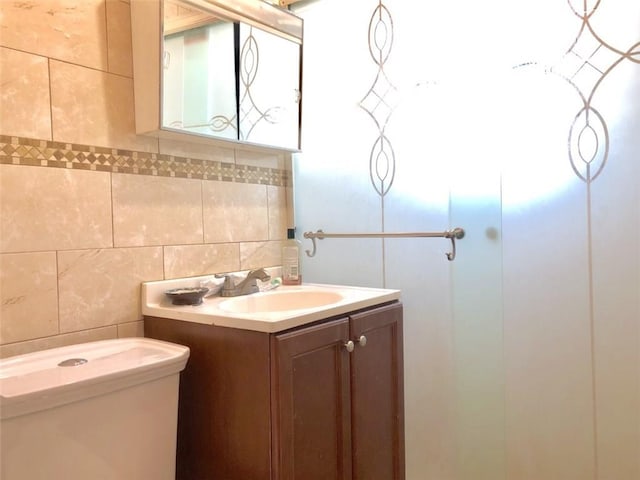 bathroom with toilet, tile walls, and vanity