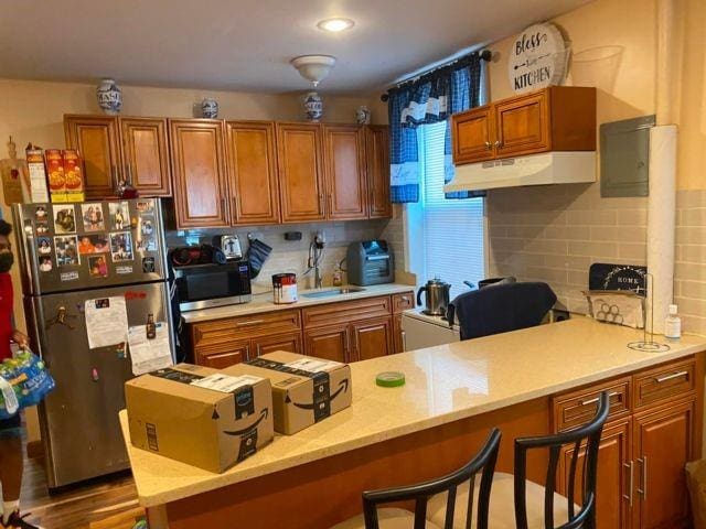 kitchen featuring a kitchen bar, tasteful backsplash, built in desk, kitchen peninsula, and stainless steel appliances