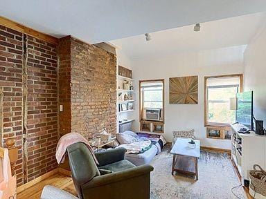 living room with brick wall and light hardwood / wood-style flooring