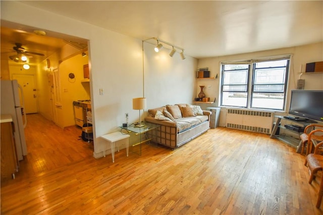 living room with light wood finished floors, radiator heating unit, and track lighting