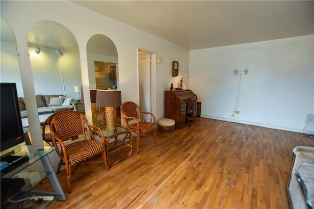 living area featuring arched walkways and hardwood / wood-style flooring