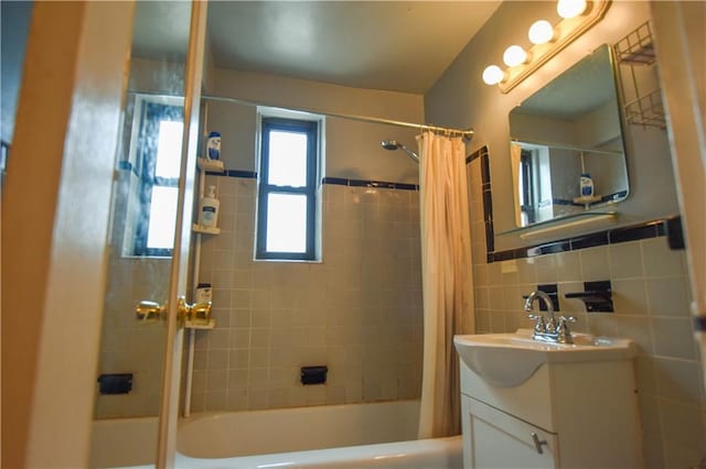 bathroom with shower / bath combo, tile walls, and vanity