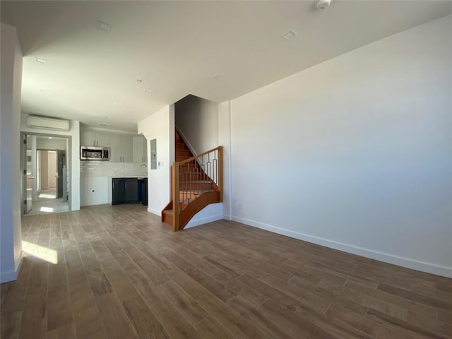 unfurnished living room with an AC wall unit and wood-type flooring