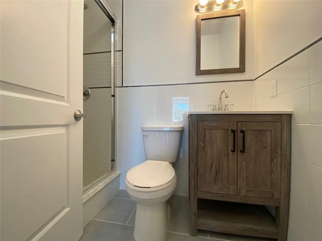 bathroom with vanity, a shower with shower door, tile patterned flooring, tile walls, and toilet