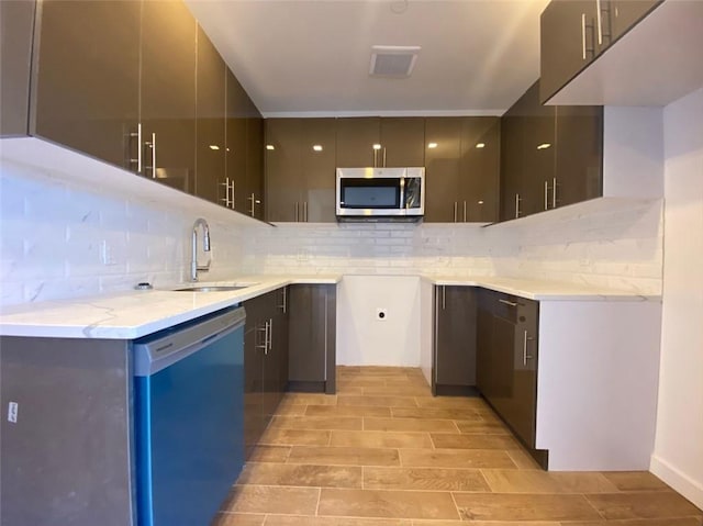 kitchen featuring stainless steel appliances, sink, light stone countertops, and backsplash