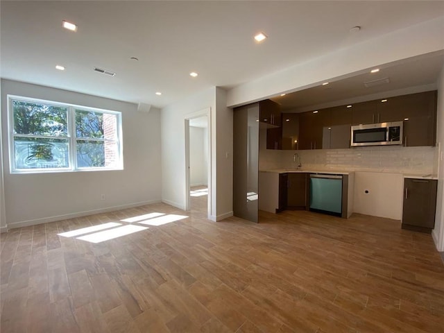 kitchen featuring sink, appliances with stainless steel finishes, hardwood / wood-style flooring, and tasteful backsplash