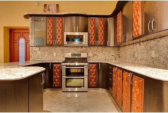 1366 70th St, Brooklyn, NY 11228 - kitchen featuring stainless steel appliances, backsplash, light stone countertops, and a peninsula