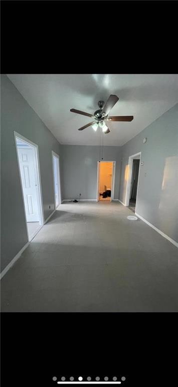 spare room with ceiling fan and baseboards