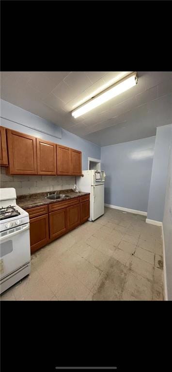 kitchen with white appliances, brown cabinets, vaulted ceiling, and light floors