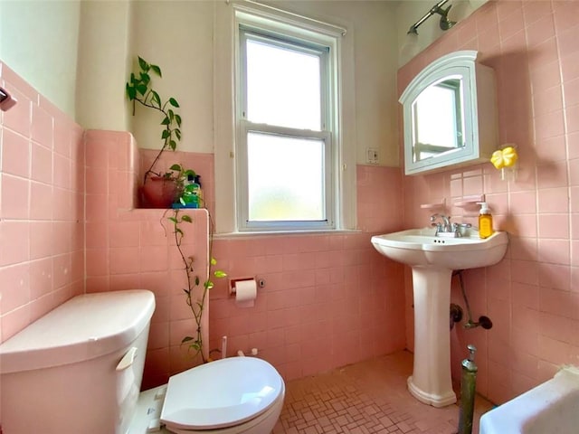 bathroom with tile patterned flooring, toilet, and tile walls