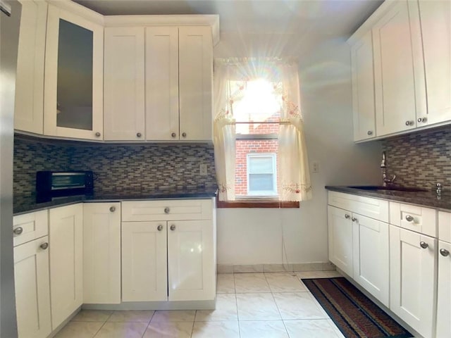 kitchen with tasteful backsplash, white cabinetry, and sink