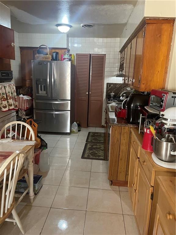 kitchen with light tile patterned flooring and stainless steel refrigerator with ice dispenser