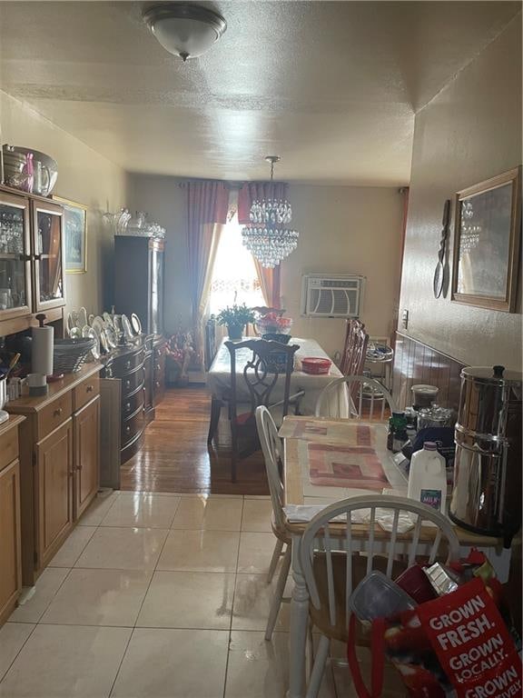 dining room with a wall mounted air conditioner, light tile patterned floors, and an inviting chandelier