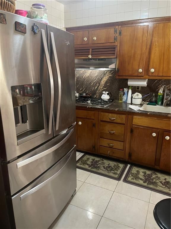 kitchen with backsplash, light tile patterned floors, and stainless steel appliances