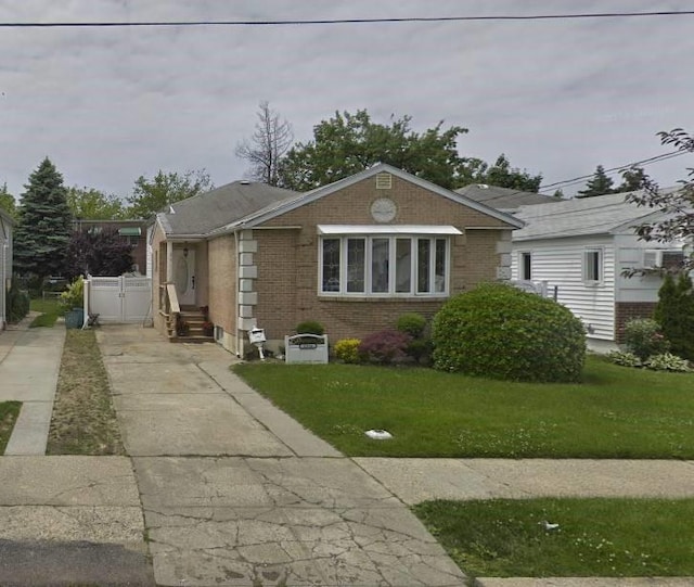 view of front of house with brick siding, driveway, fence, and a front lawn