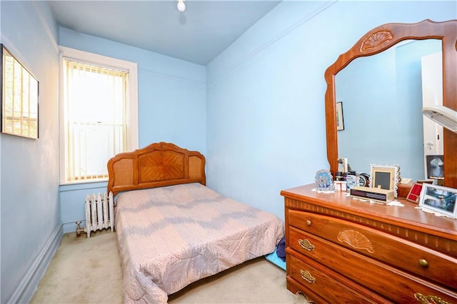 bedroom featuring radiator, light carpet, and baseboards