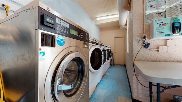 laundry area with independent washer and dryer and a textured ceiling