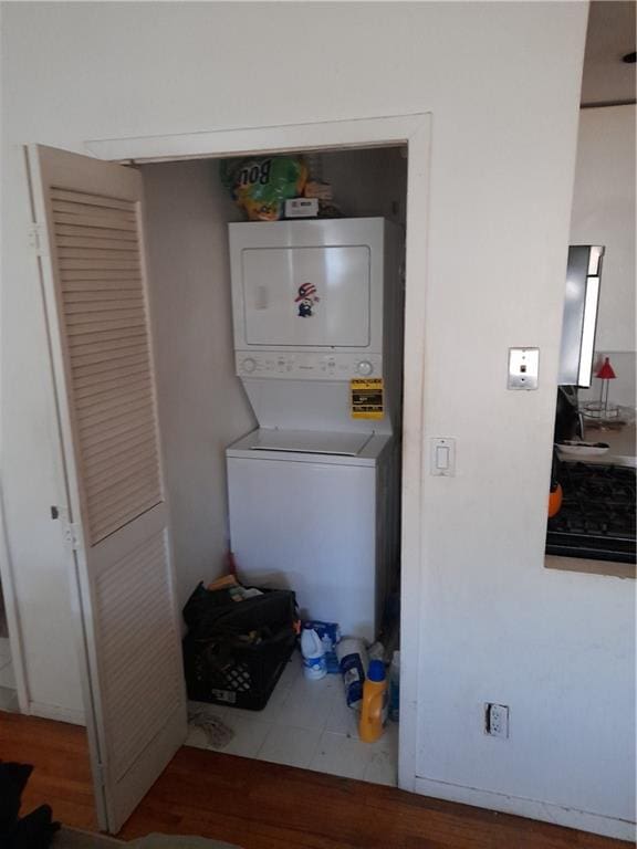 laundry room with laundry area, wood finished floors, and stacked washer and clothes dryer