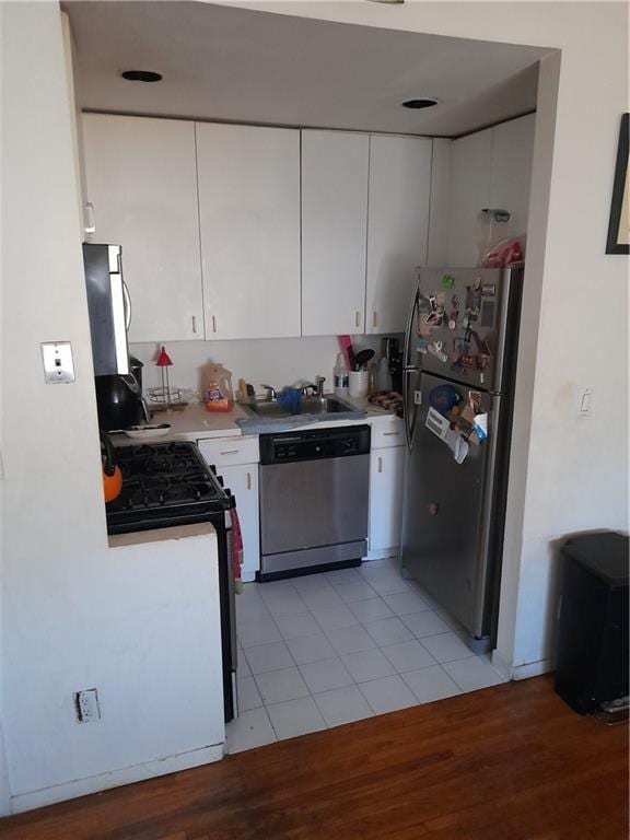 kitchen with stainless steel appliances, light countertops, white cabinets, and light wood-style flooring