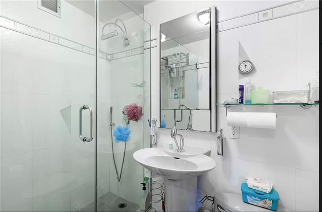 bathroom with a shower with shower door, tile walls, and toilet