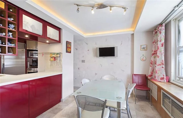 kitchen with a raised ceiling, kitchen peninsula, and appliances with stainless steel finishes