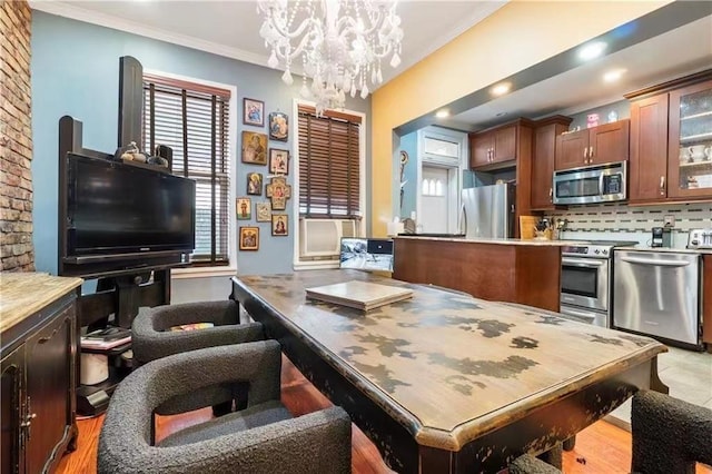 kitchen with decorative backsplash, ornamental molding, stainless steel appliances, a notable chandelier, and hanging light fixtures