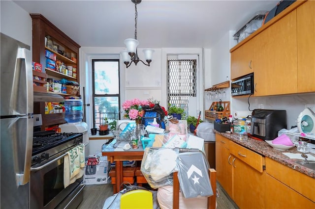 kitchen featuring appliances with stainless steel finishes, dark wood-type flooring, stone countertops, an inviting chandelier, and decorative light fixtures