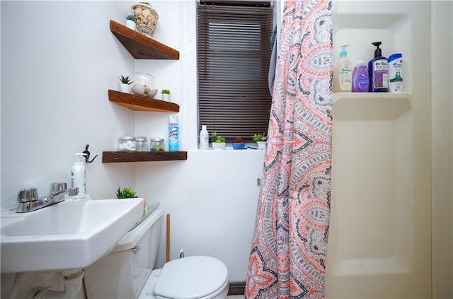 bathroom featuring a shower with curtain, sink, and toilet